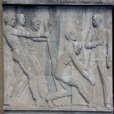 Eines von zwei Reliefs am Eingang mit Arbeiterdarstellungen.