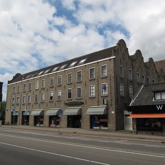 Complex evenwijdig aan de straat gelegen pakhuizen waarvan de parallel lopende zadeldaken aan voor- en achterzijde worden afgesloten door klokgevels met tussendekplaten