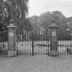 Vier gemetselde hekpalen met hardstenen ornamenten en smeedijzeren hek