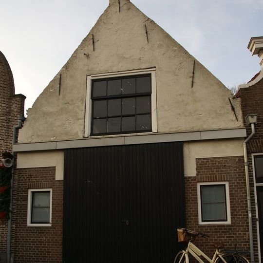 Huis met gepleisterde puntgevel met in het zoldervenster roedenverdeling stijl