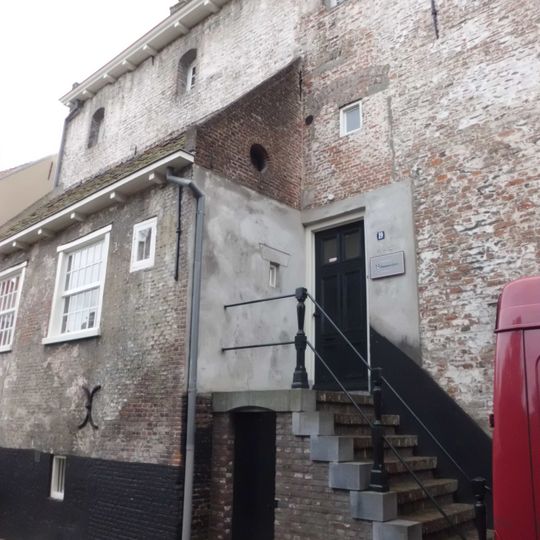 Huis met hoog oprijzende gewitte gevel. Hijsluik, rechte daklijst doorsnijdend; hoog zadeldak. Op bovenverdieping kleine vensters. Aanbouw tegen de stadszijde. Dichtgemetselde vensters