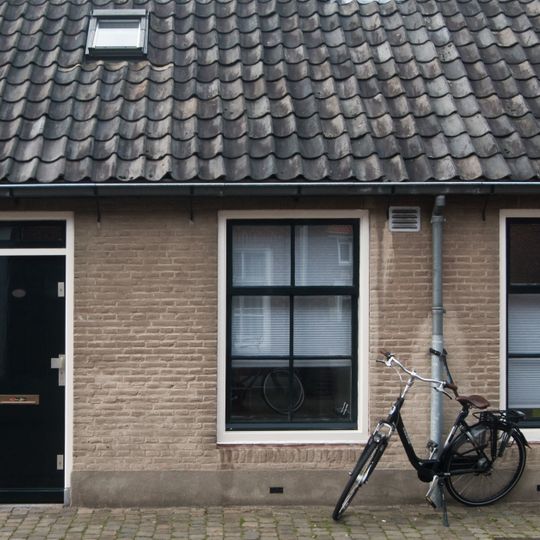 19e eeuws arbeiderswoninkje zonder verdieping onder met blauwe Hollandse pannen gedekt zadeldak, dat doorloopt over de buurpanden