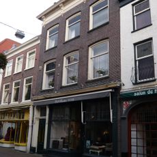 Pand met rechte kroonlijst rustend op consoles. Beneden verbouwd