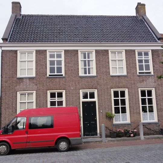 Dwarshuis onder pannen zadeldak tussen zij; topgevels, met geprofileerde kroonlijst