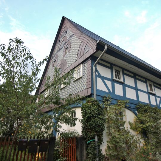 Wohnstallhaus mit Oberlaube, Remisenanbau mit zwei großen Toren und Scheune im rechten Winkel, weiteres Wohnstallhaus in der Flucht der Scheune und südliches Wohnstallhaus sowie Granitzaunspfosten der Nutzgarteneinfriedung Kumschütz 8
