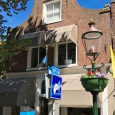 Pand onder zadeldak tegen klokgevel met gebeeldhouwde aanzetkrullen en verhoogde bekroning