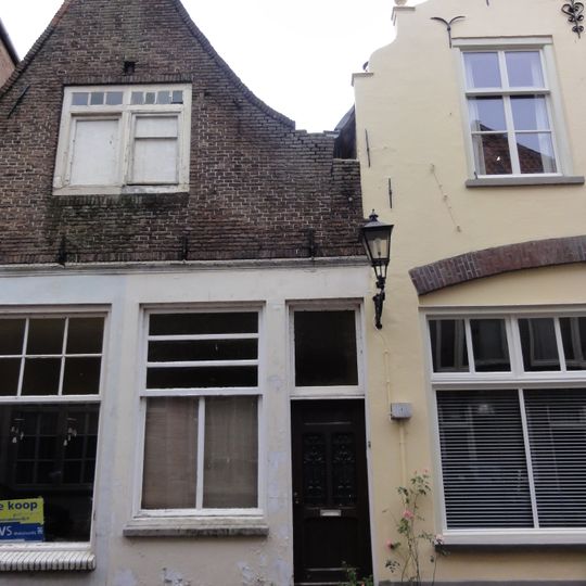 Huis met ingezwenkte halsgevel, waarlangs uitgemetselde rollaag. Een geheel met nr 18