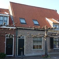 Huis onder zadeldak met langsgevel aan de straat. Schuiframen met negen ruiten