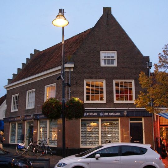 Pand met bakstenen trapgevel boven moderne winkelpui op de scherpe hoek met het venedie