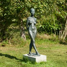Stehende Frau, aus Metall, auf Betonsockel
