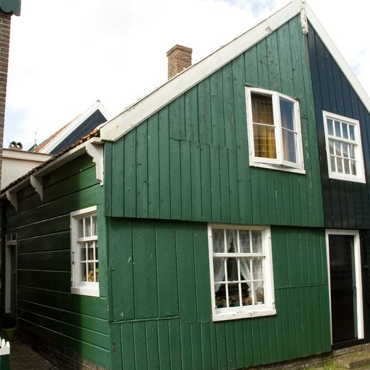 Perceelsgedeelte van een houten huis met brede topgevel