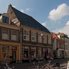 Hoekpand met jongere pui in de voorgevel en waterlijsten en fragmenten van dichtgemetselde zandstenen kozijnen in de zijgevel