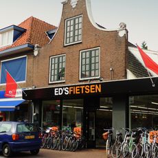 Pand onder zadeldak tegen klokgevel met gebeeldhouwde aanzetkrullen en deklijsten en in de gezwenkte bekroning een wapencartouche