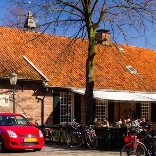 Teylershuis met houten geveltop en bakstenen inrijpoort, op welker sluitsteen het tijdvers