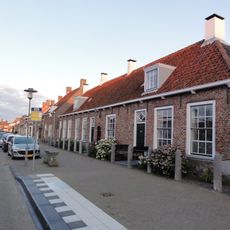 Complex dorpshuizen onder een kap, nok evenwijdig aan de straat. Schuifvensters. Tussen nr 94 en 96 een boogpoortje, hierboven een sierankers