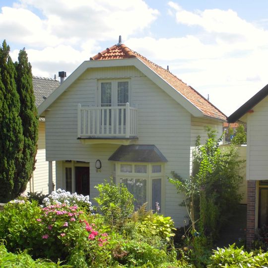 Houten huis met gerabatte wanden met zolderverdieping onder zadeldak met wolfeind