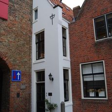 Half puntgeveltje, gepleisterd, tegen de poort