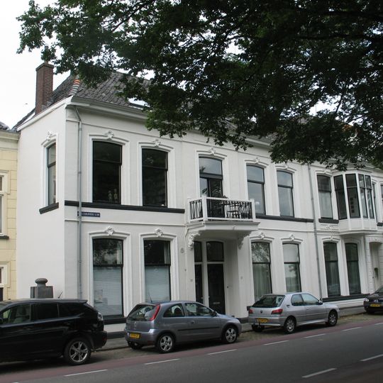 Breed pand met gepleisterde lijstgevel met zijlisenen onder dwars schilddak